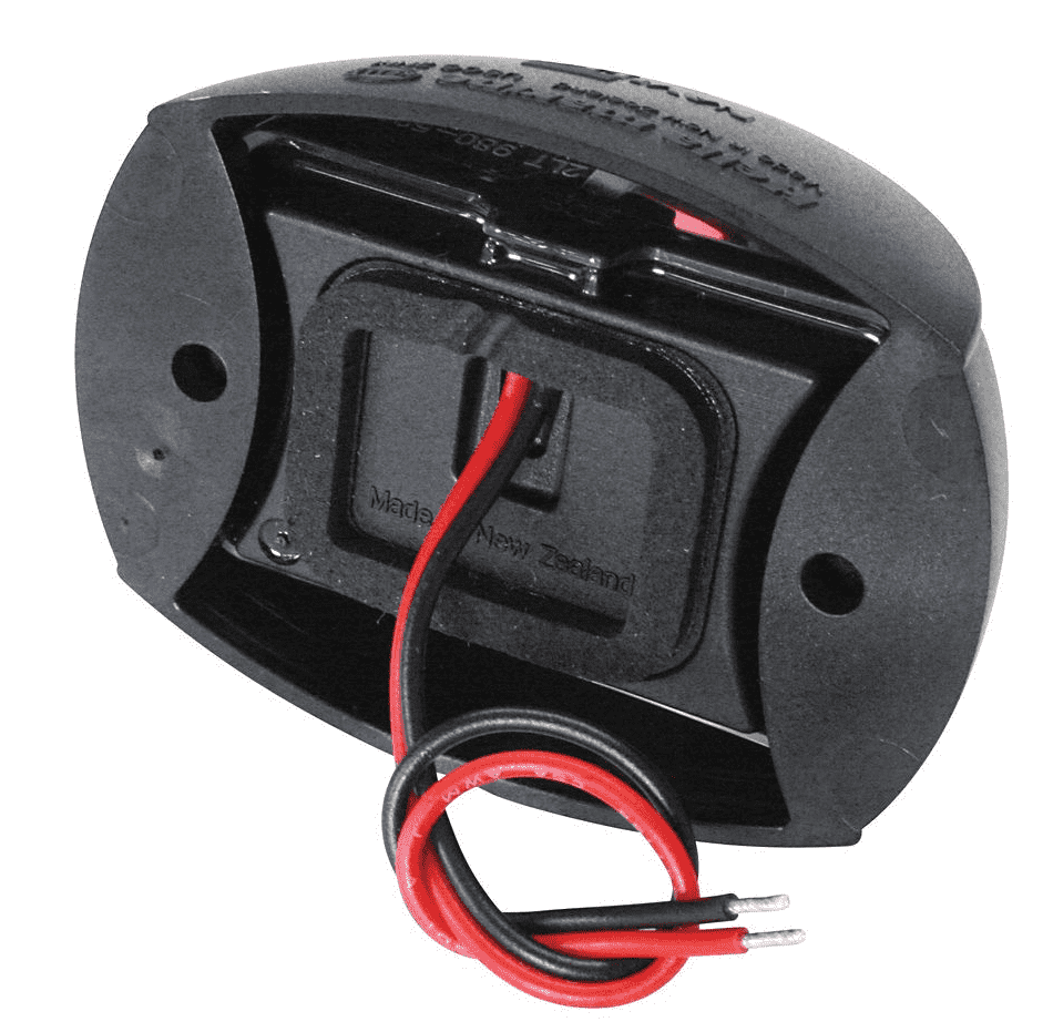 Das Bild zeigt eine schwarze Navigationslampe mit abgerundeter Gehäuseform. Zwei isolierte Kabel, eines rot und eines schwarz, ragen aus einer Öffnung an der Rückseite heraus. Die Schraublöcher für die Befestigung sind sichtbar. Auf dem Kunststoffgehäuse sind Prägungen und Schrift zu erkennen. Die Rückseite trägt die Gravur "Made in New Zealand".